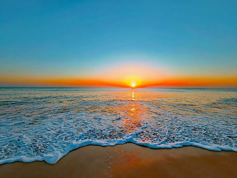 Bright, orange sun rising up from the horizon over the shores of the Atlantic