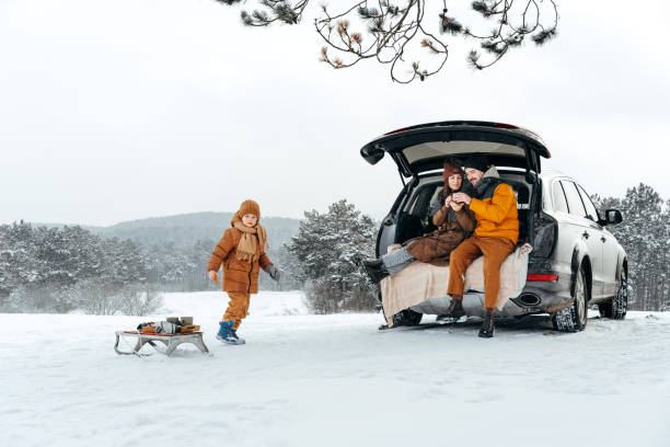 winter portrait of a family sit on car trunk enjoy their vacation in forest - travel adventure winter cold imagens e fotografias de stock