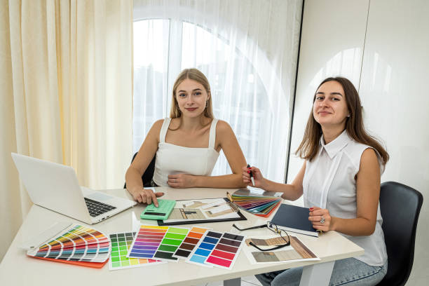 istock two  perfect female workers in white blouses work at a spacious table on a new room design. 1390216138