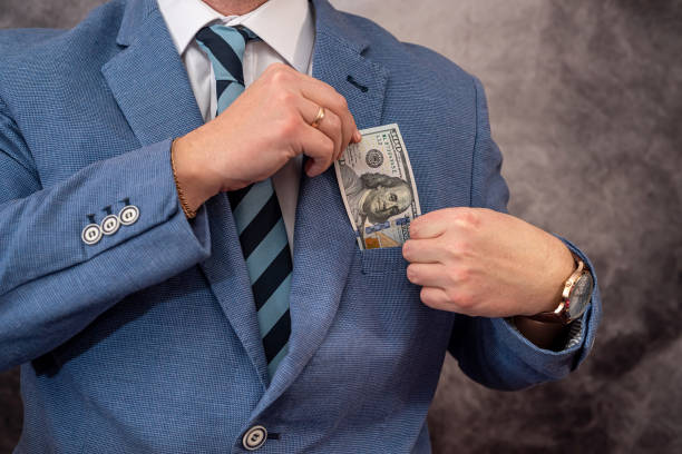 istock Young man in suit putting dollar bills in his pocket 1390216401