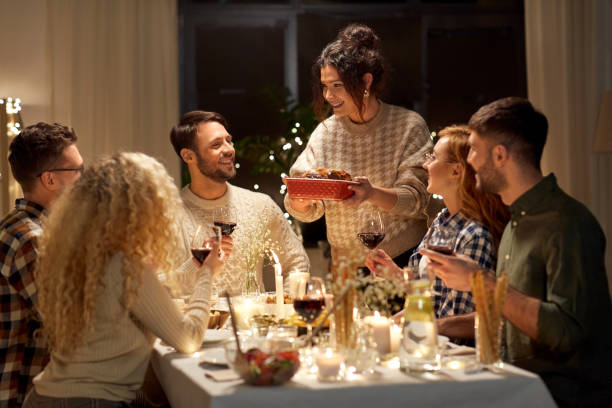 amigos felices teniendo la cena de navidad en casa - party host fotografías e imágenes de stock