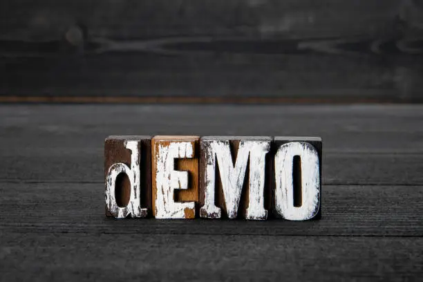 Photo of DEMO. Wooden alphabet letters on a dark textured background