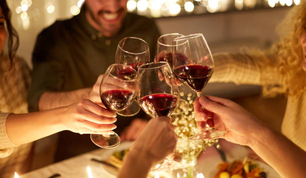 glückliche freunde trinken rotwein bei weihnachtsfeier - rotwein stock-fotos und bilder