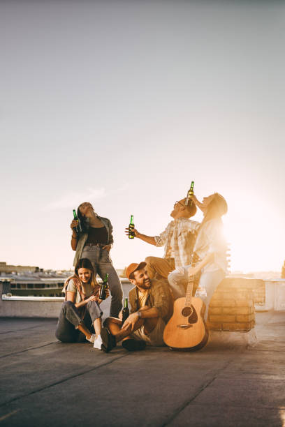 istock Cheerful friends drinking beer on a rooftop at sunset. 1390218148