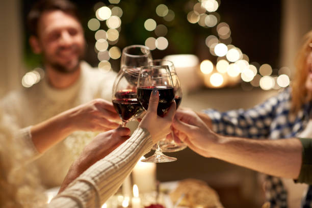 happy friends drinking red wine at christmas party stock photo