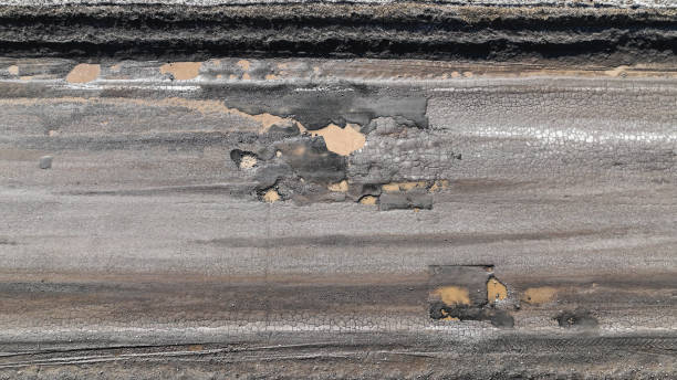Broken old asphalt road outside the city. Pits and potholes. Aerial view stock photo
