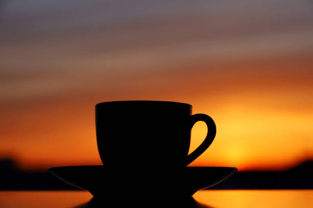 istock Black silhouette of coffee or tea cup on sunset background 1390219365