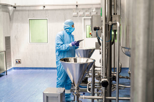 Full length view of a researcher in an industrial laboratory facility Full length view of a researcher in protective workwear in an industrial laboratory facility drug manufacturing stock pictures, royalty-free photos & images