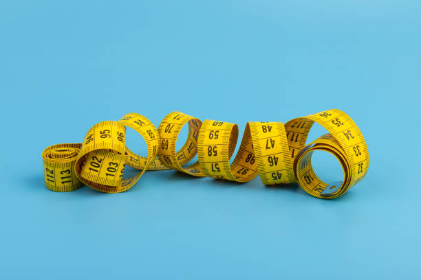 istock Yellow spiral tape measure on blue background. Centimeter. Space for text. 1390221909