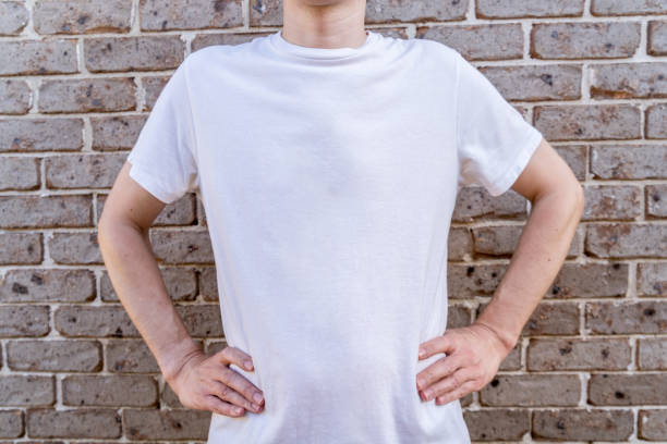 istock Man wearing mockup white t-shirt on brick wall background. Template copy space 1390222086
