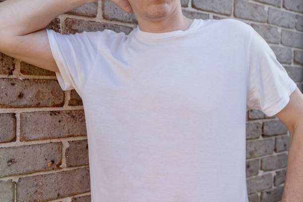 istock Man wearing mockup white t-shirt on brick wall background. Template copy space 1390222129