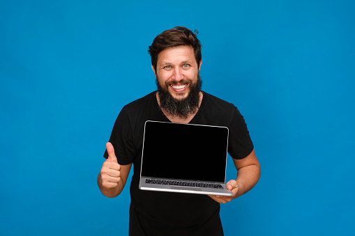 Portrait of smiling man holding Digital Computer, leptop blue background