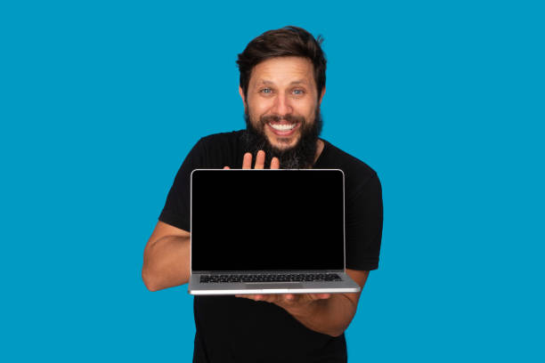Portrait of smiling man holding Digital Computer, leptop blue background stock photo