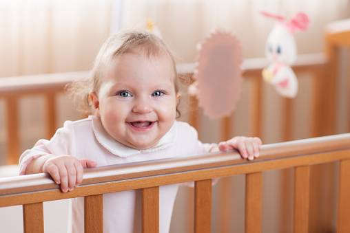 Portrait of a happy and laughing baby in a crib