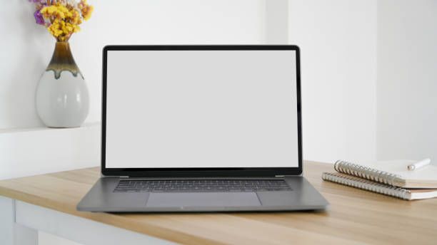 istock Modern notebook laptop computer white screen mockup is on a minimal wood table 1390227939