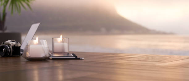 Wood table with copy space and romantic candle lights, retro camera and accessories against blurred sunset at the sea or ocean view in the background. 3d rendering, 3d illustration