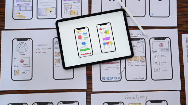 Web developer workplace with sketches of mobile application on wooden table. Flat lay, Top view.