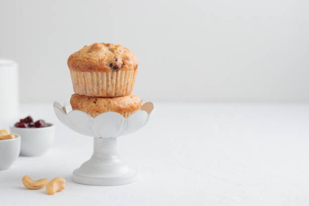 Fresh muffins in a cake stand on a white table