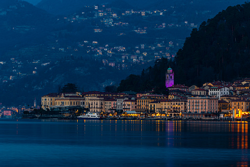 The bay and marina of Como, Italy.  There is a tourist taking a photograph beside the railings.