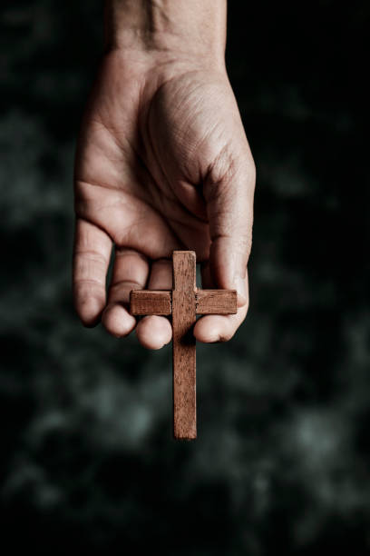 man with a wooden cross in his hand closeup of a man with a wooden cross in his hand, on a black mottled background the passion of jesus stock pictures, royalty-free photos & images