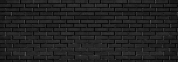 istock Black shabby brick wall wide texture with hard light. Dark grey brickwork abstract panoramic grunge background 1390239363