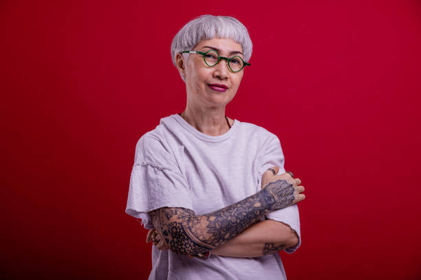 smiling hip senior woman portrait on red background with tatoo. - dövme yaptırmak fotoğraflar stok fotoğraflar ve resimler