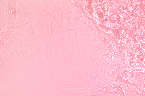 Transparent pink colored clear water surface texture with ripples, splashes and bubbles. Abstract nature background Water waves in sunlight with copy space Cosmetic moisturizer micellar toner emulsion