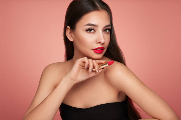 istock A beautiful young woman applying lipstick 1390242213