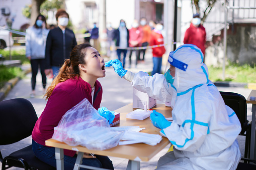 In April 2022, a medical worker wearing protective clothing was conducting nucleic acid testing and sampling for a woman in Shanghai, China。Nucleic acid test method