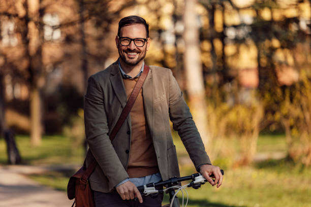 istock Portrait of a smiling man, holding a bicycle handlebar, walking. 1390243405