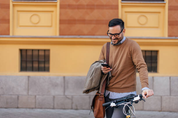 istock Smiling adult man, standing next to his bake, using the phone. 1390243479