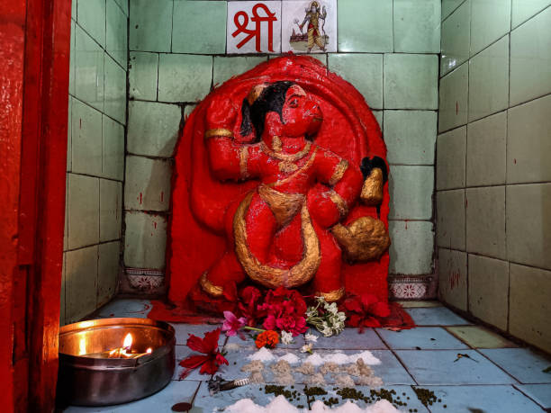 Stock photo of saffron color painted lord Hanuman idol in the temple, devotees offer flowers , oil and vermilion to god. Picture captured under natural light, at Khidrapur, India. stock photo