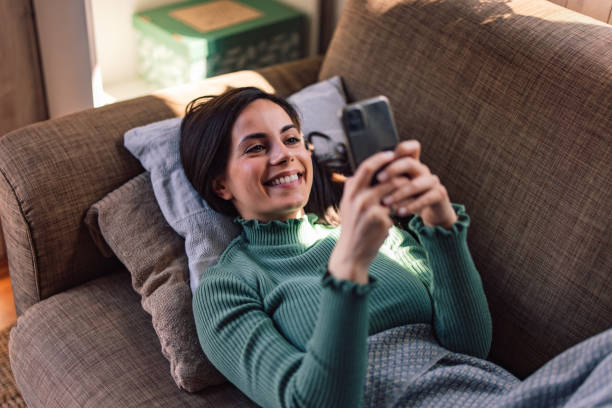 istock Close up of a relaxed brunette woman, using a phone while resting in her bed. 1390243896