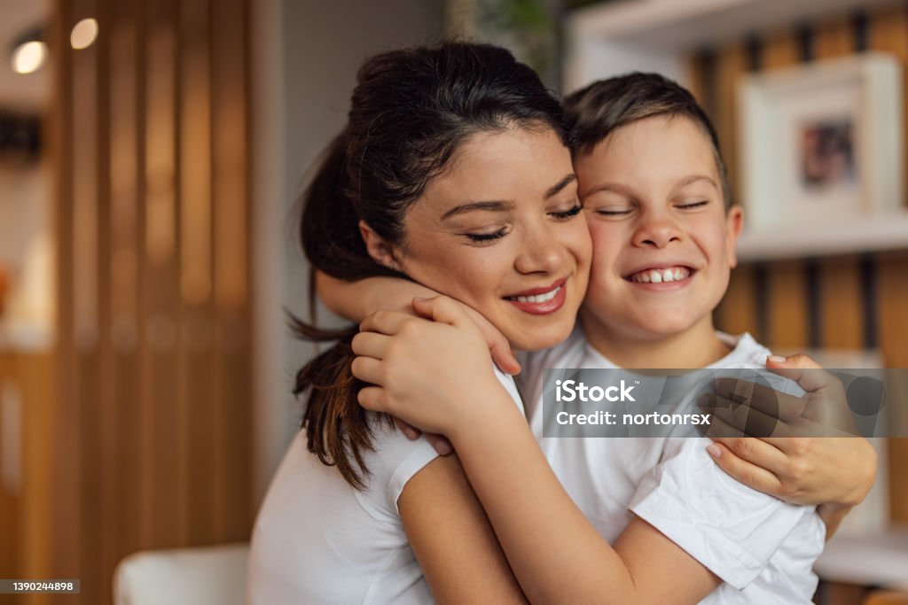 Close up of an adult mother hugging her male child. Smiling family in a hug, mother and young son. Mother Stock Photo