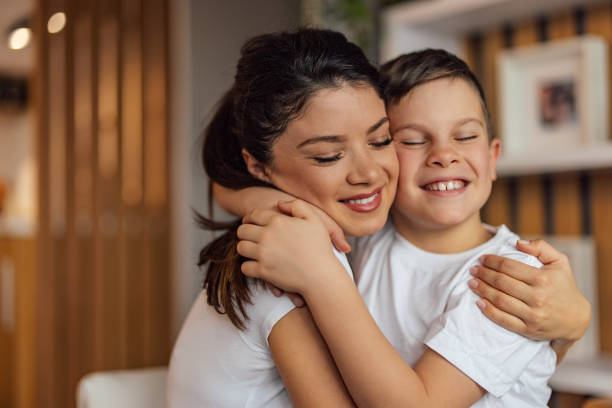 Close up of an adult mother hugging her male child. stock photo