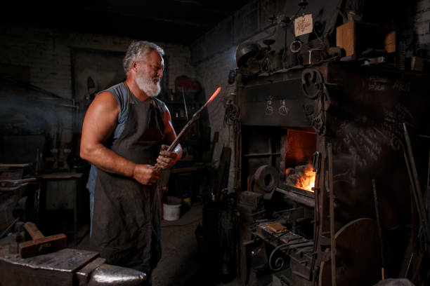 istock Blacksmith craftsman in apron works in blacksmith's shop 1390249976
