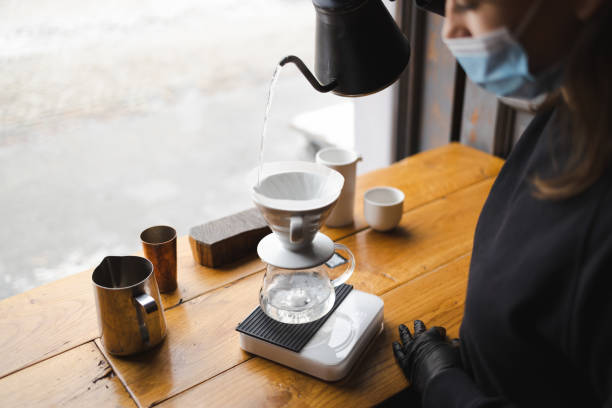 la ragazza prepara il caffè attraverso un filtro in un metodo a goccia - brown candid caffein drink foto e immagini stock