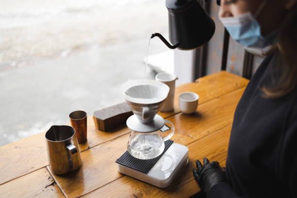 la ragazza prepara il caffè attraverso un filtro in un metodo a goccia - brown candid caffein drink foto e immagini stock