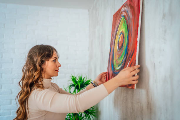 istock Woman hanging picture on wall 1390250810