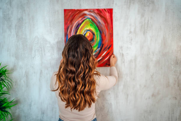 istock Woman hanging picture on wall 1390250827