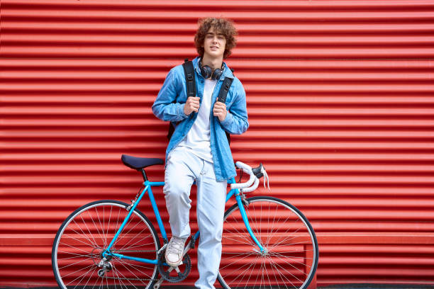 istock Smiling man leaning on bicycle and ribbed red wall 1390251475