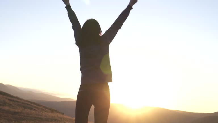 symbol of the winner girl at sunrise raises her hands,slow mo