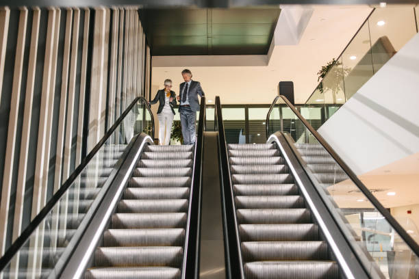 istock Business people moving down the escalator 1390254125