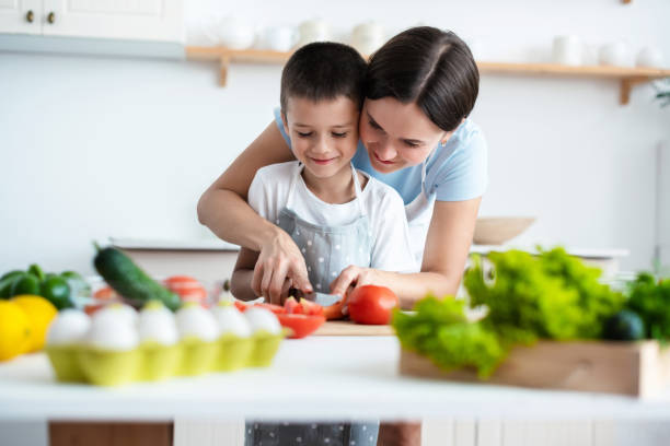 istock Cheerful mother helping her son to cook 1390254244