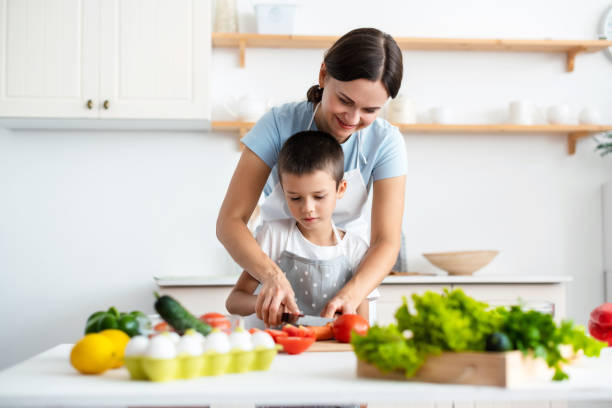 istock Cheerful mother helping her son to cook 1390254245
