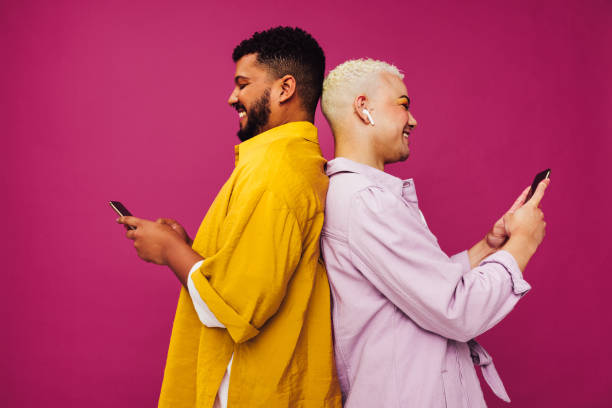 istock Smiling gay couple using mobile phones in a studio 1390254249