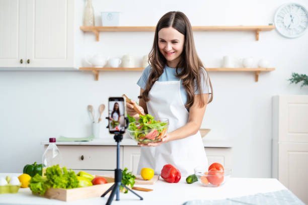 istock Young woman chef cooking while streaming online for webinar masterclass lesson at home. 1390254952
