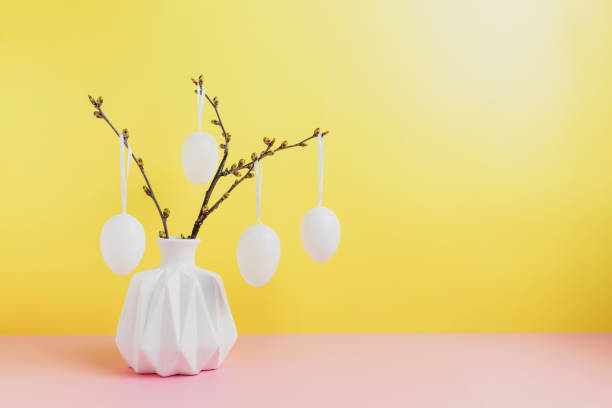 buone vacanze di pasqua, prossima primavera. rami in vaso bianco, uova appese - easter ornament foto e immagini stock