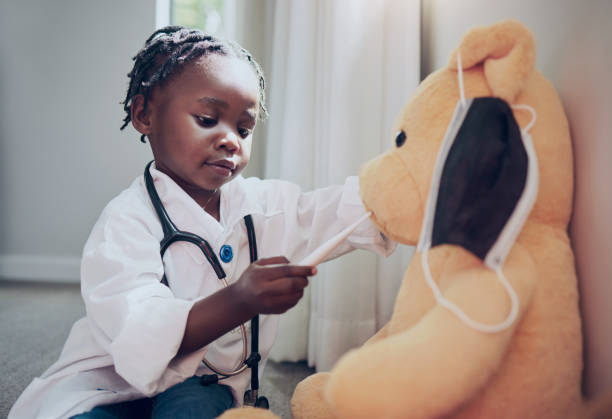 shot of a little girl pretending to be a doctor while examining her teddybear at home - imagination imagens e fotografias de stock