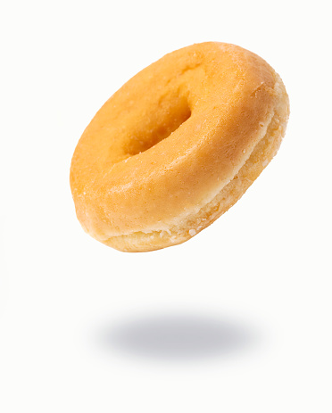 Freshly baked flying sugar plain donut on white background.